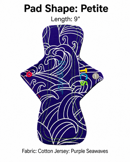 A reusable menstrual pad shown on a white background with text reading 'Pad Shape: Petite', 'Length: 9"', and 'Fabric: Cotton Jersey: Purple Seawaves'. The pad has a dark purple base with white wave-like pattern lines and small colorful pin-attachment dots in red, blue, yellow, and green.