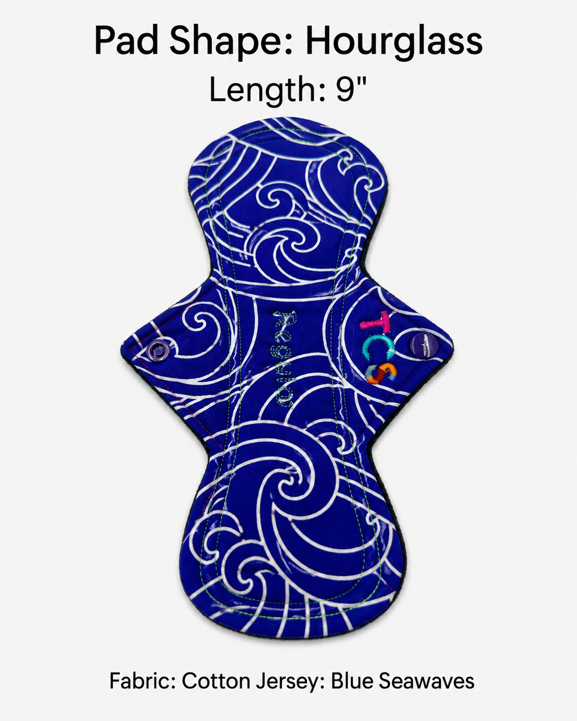 An hourglass-shaped cotton jersey menstrual pad with a white swirling wave pattern on a deep blue background, shown on a light gray background with text reading 'Pad Shape: Hourglass', 'Length: 9"', and 'Fabric: Cotton Jersey: Blue Seawaves'.